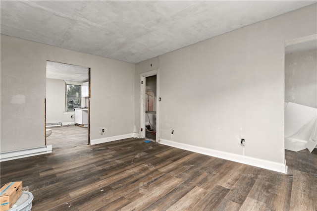 spare room featuring baseboard heating and dark wood-type flooring