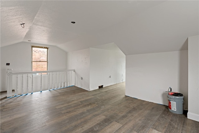 bonus room featuring a textured ceiling, dark wood-type flooring, and vaulted ceiling