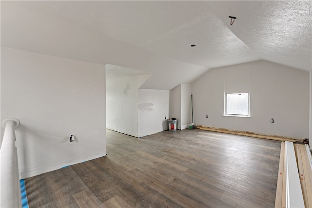 additional living space with lofted ceiling, a textured ceiling, and dark wood-type flooring