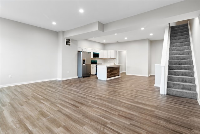 unfurnished living room featuring sink and hardwood / wood-style flooring