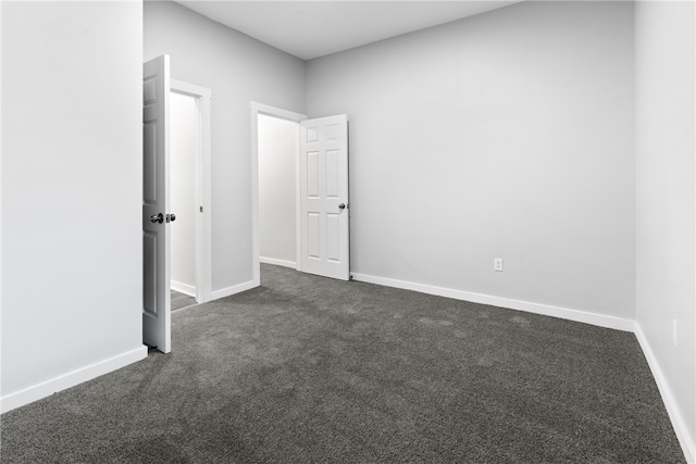 unfurnished room featuring dark carpet