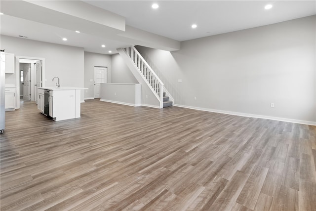 unfurnished living room with sink and light hardwood / wood-style floors