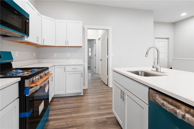 kitchen featuring sink, black appliances, hardwood / wood-style flooring, and white cabinets