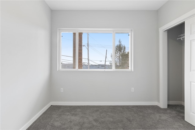 unfurnished bedroom with a closet and dark carpet