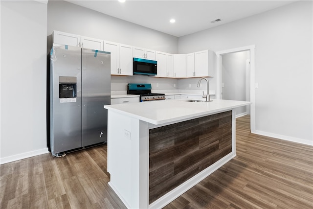 kitchen with dark hardwood / wood-style flooring, stainless steel refrigerator with ice dispenser, a center island with sink, and stove