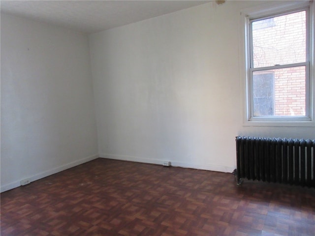 empty room with dark parquet floors and radiator