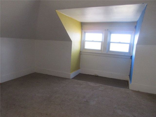 bonus room with dark carpet and vaulted ceiling