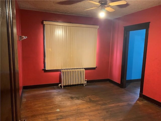 spare room with radiator, dark wood-type flooring, ceiling fan, and a textured ceiling