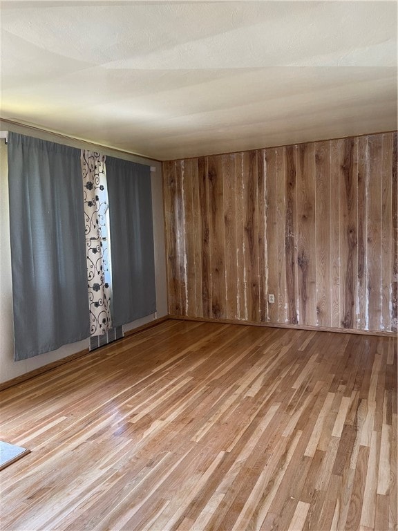 spare room featuring wood walls and hardwood / wood-style floors