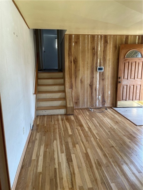 staircase with wood walls, hardwood / wood-style floors, and vaulted ceiling