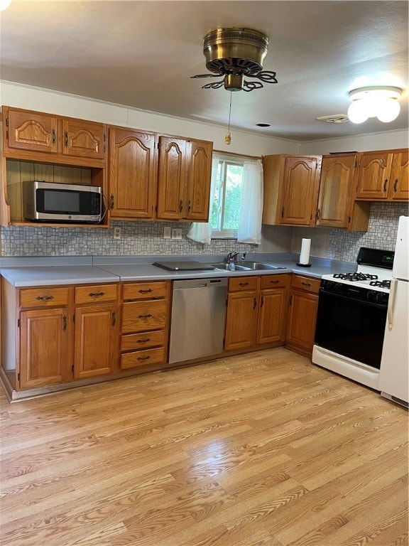 kitchen featuring stainless steel appliances, backsplash, light hardwood / wood-style floors, and ceiling fan