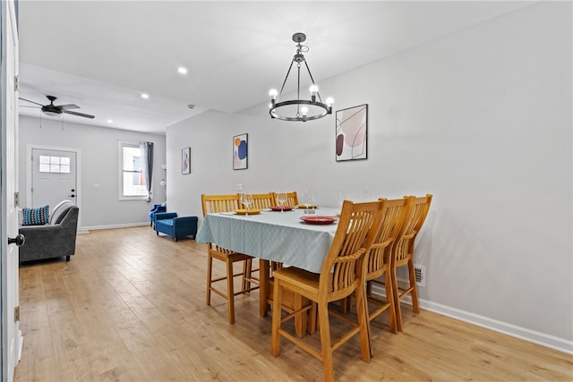 dining area with ceiling fan with notable chandelier and light wood-type flooring