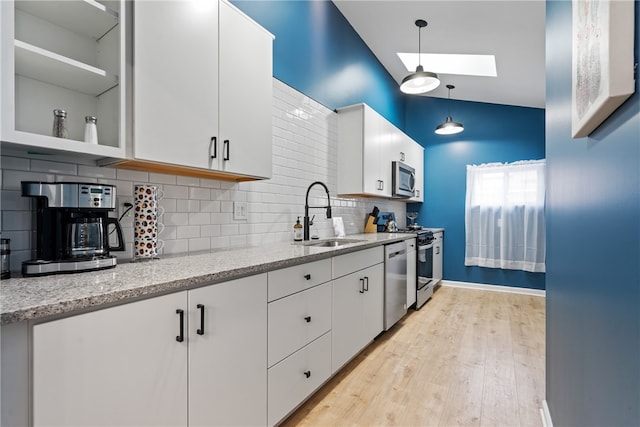 kitchen with backsplash, light hardwood / wood-style flooring, lofted ceiling with skylight, white cabinetry, and sink