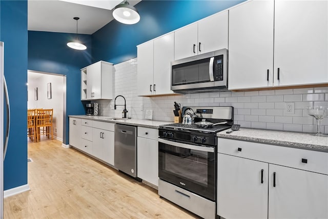 kitchen featuring white cabinets, sink, backsplash, stainless steel appliances, and light hardwood / wood-style flooring