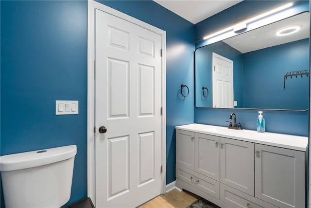 bathroom with hardwood / wood-style floors, vanity, and toilet