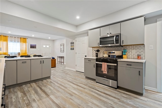 kitchen with gray cabinetry, light wood-type flooring, and stainless steel appliances