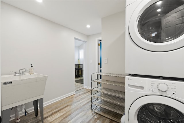 laundry area with sink, stacked washer / dryer, and light wood-type flooring