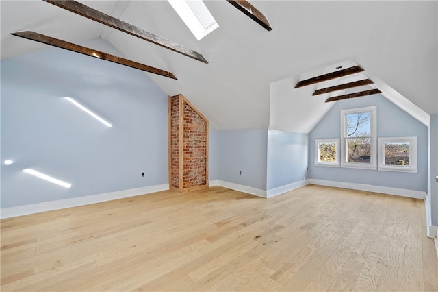 bonus room featuring brick wall, light wood-type flooring, and vaulted ceiling with skylight