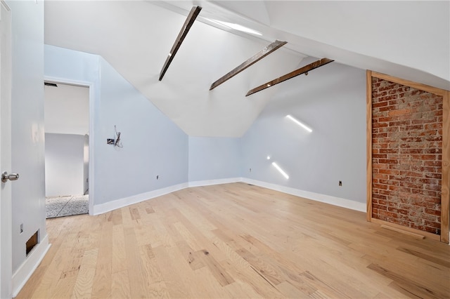 bonus room featuring light hardwood / wood-style flooring, lofted ceiling, and brick wall