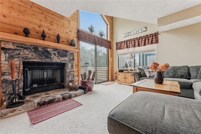 carpeted living room featuring a high ceiling, a fireplace, and wooden walls