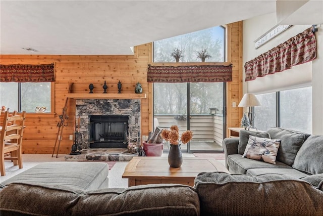 living room featuring carpet floors, wood walls, and a stone fireplace