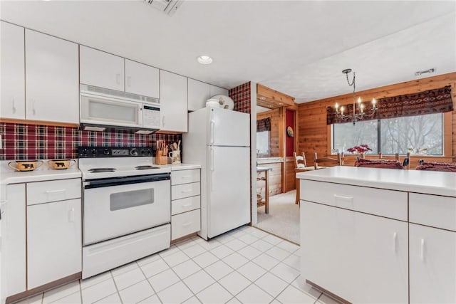 kitchen featuring an inviting chandelier, white cabinetry, tasteful backsplash, white appliances, and pendant lighting