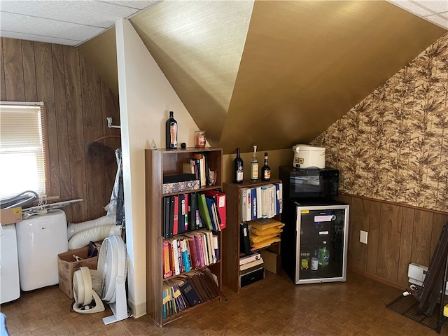 office space with lofted ceiling, wooden walls, and dark parquet floors