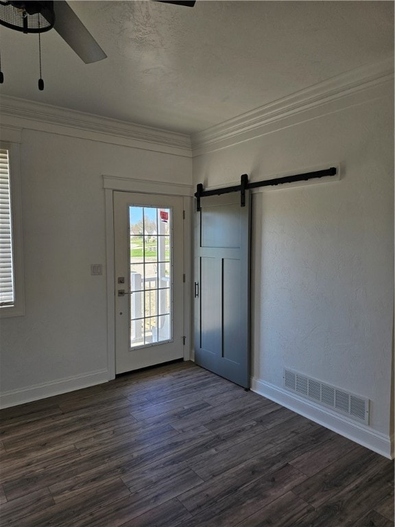 interior space featuring ornamental molding, dark wood-type flooring, a barn door, and ceiling fan