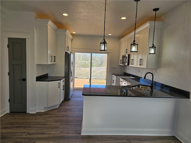 kitchen featuring kitchen peninsula, stainless steel appliances, sink, and decorative light fixtures