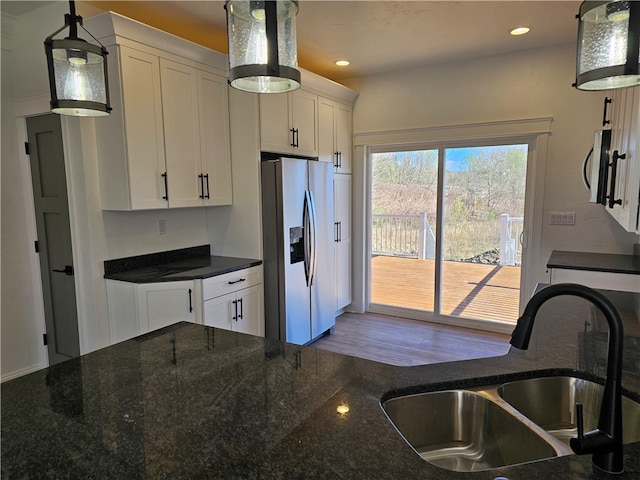 kitchen featuring stainless steel appliances, sink, dark stone counters, white cabinets, and pendant lighting