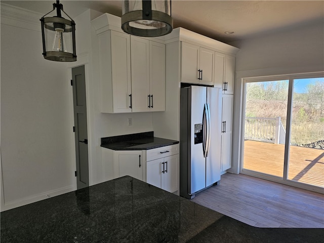 kitchen featuring hanging light fixtures, stainless steel fridge, white cabinetry, and light wood-type flooring