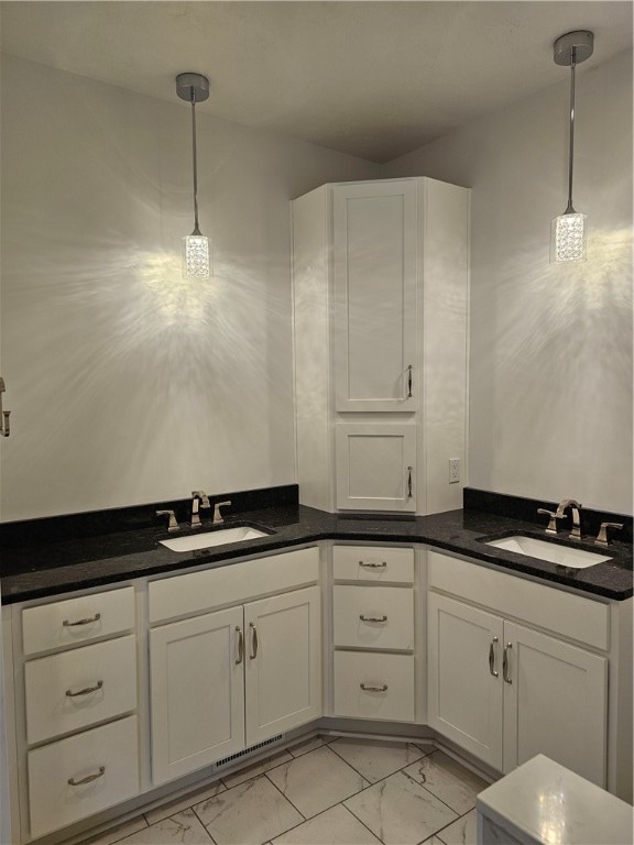 kitchen with white cabinetry, hanging light fixtures, and sink