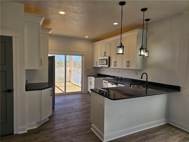 kitchen with decorative light fixtures, dark hardwood / wood-style floors, sink, white cabinets, and kitchen peninsula