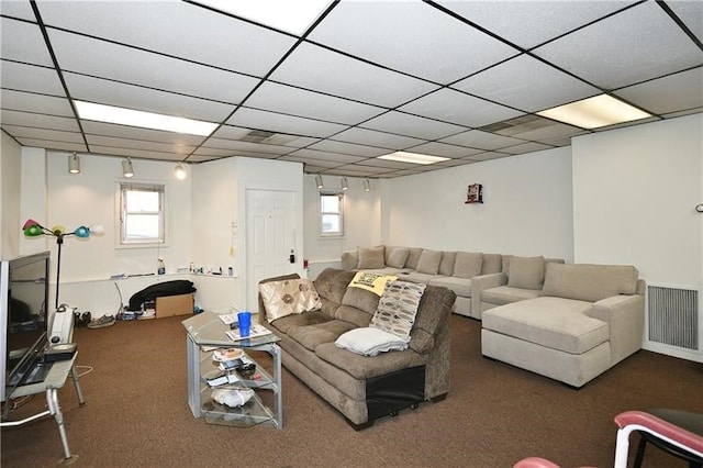 living room featuring a drop ceiling and dark colored carpet