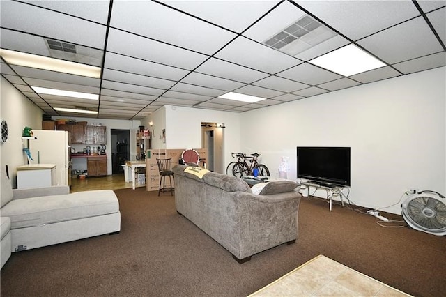 living room with dark tile flooring and a paneled ceiling