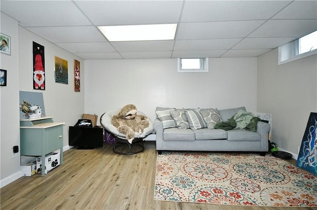 living room with a wealth of natural light, light hardwood / wood-style flooring, and a paneled ceiling