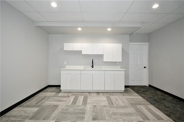 kitchen with sink, white cabinets, and a paneled ceiling