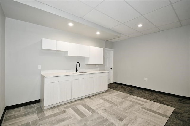 kitchen featuring white cabinets, sink, and a drop ceiling