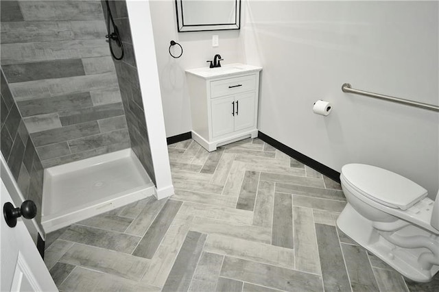 bathroom featuring parquet flooring, vanity, toilet, and tiled shower