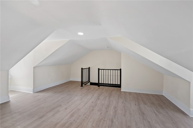 bonus room with vaulted ceiling and light wood-type flooring