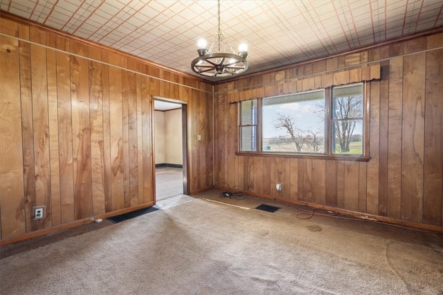 unfurnished room featuring wood walls, a notable chandelier, and light carpet