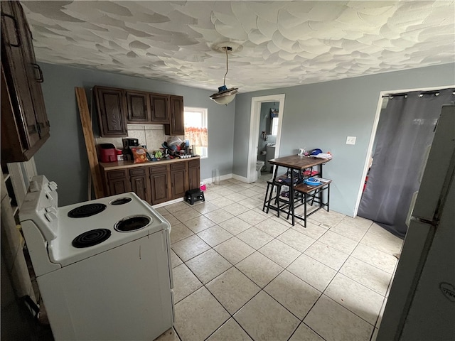 kitchen with black refrigerator, light tile flooring, backsplash, electric stove, and a textured ceiling