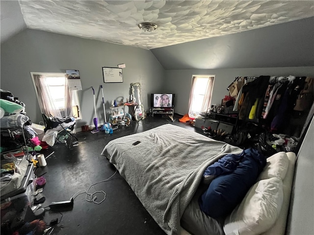 bedroom featuring a textured ceiling, vaulted ceiling, and multiple windows