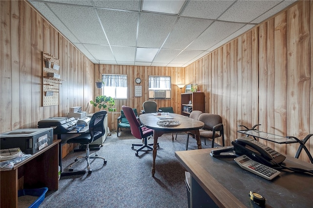 office area featuring a drop ceiling, wooden walls, and carpet flooring