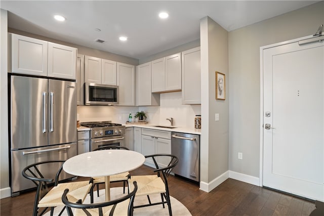 kitchen with appliances with stainless steel finishes, dark hardwood / wood-style floors, sink, and white cabinets