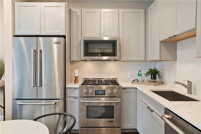 kitchen with high end appliances, white cabinetry, and sink