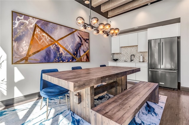 dining room with beamed ceiling, sink, an inviting chandelier, and hardwood / wood-style flooring