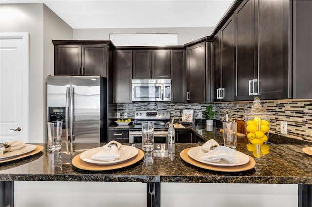 kitchen featuring appliances with stainless steel finishes, backsplash, and dark stone countertops