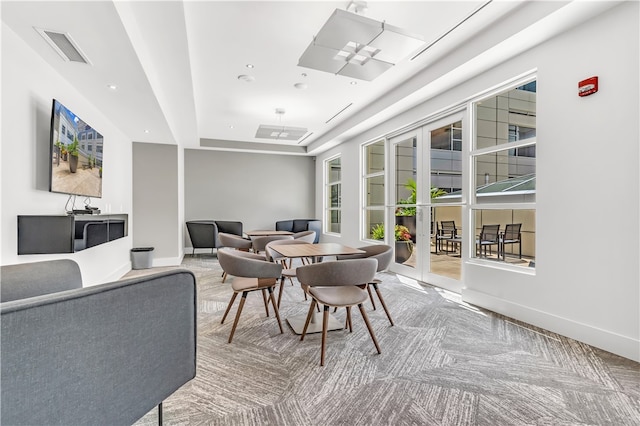 interior space with light carpet, ceiling fan, and a tray ceiling