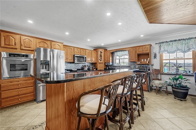 kitchen featuring appliances with stainless steel finishes, light tile floors, a kitchen island, and a breakfast bar